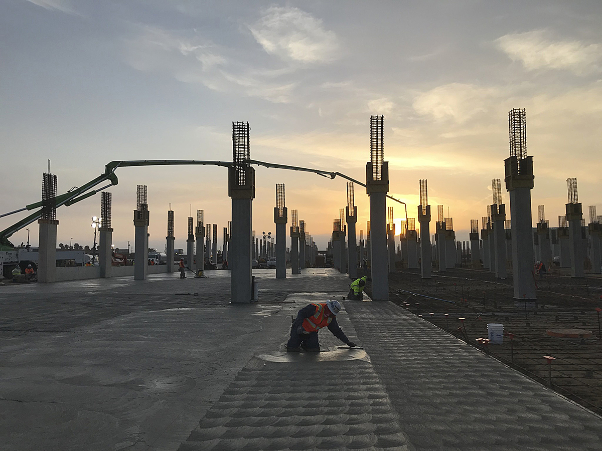 A craft worker putting the finishing touches by hand on the slab-on-grade pour at the Intermodal Transportation Facility – West