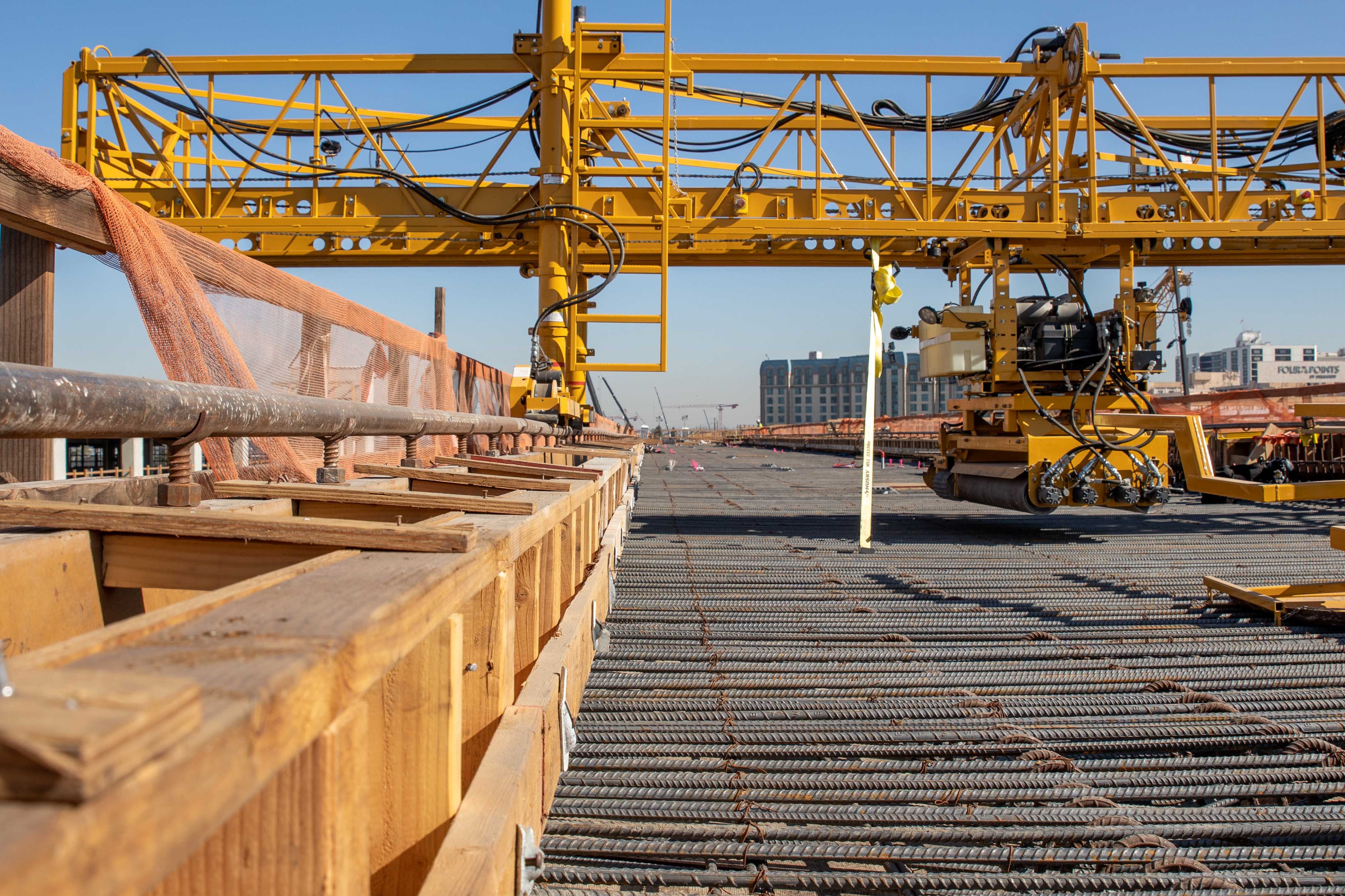 Machinery used to spread concrete is installed on rails prior to the final concrete placement for the guideway superstructure.